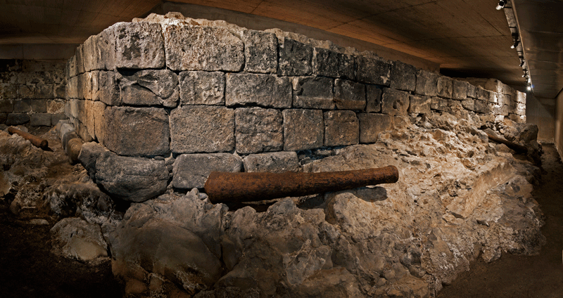 Ruïnes van een historische muur op Tenerife verlicht onder een betonnen dak.