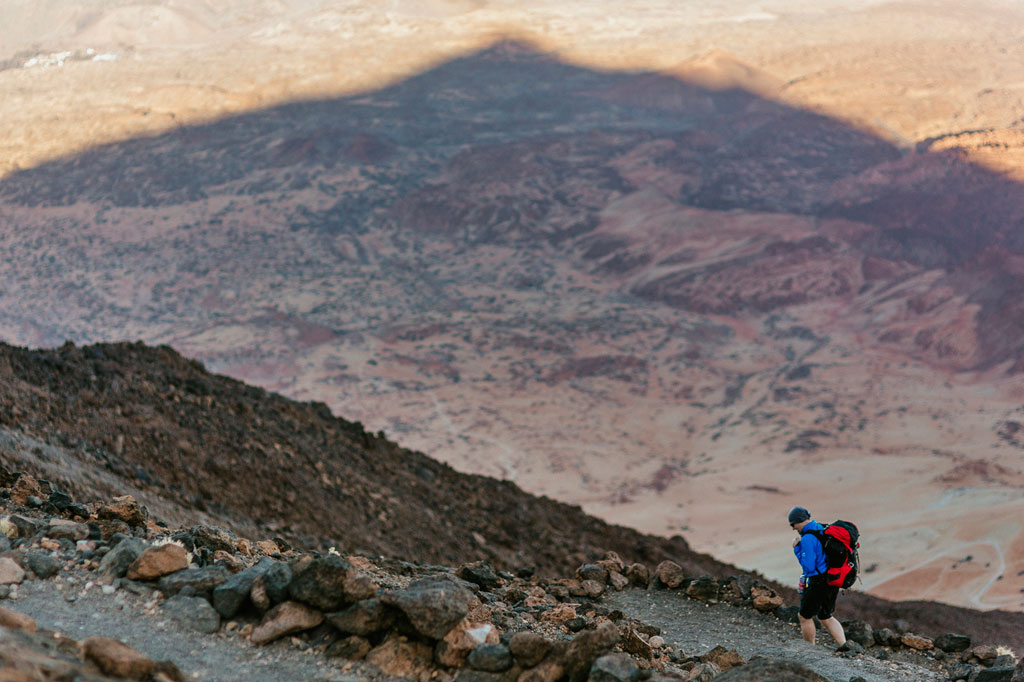 Persoon die op een rotsachtig pad op de berg Teide, Tenerife, loopt, met een dorre achtergrond in het landschap.