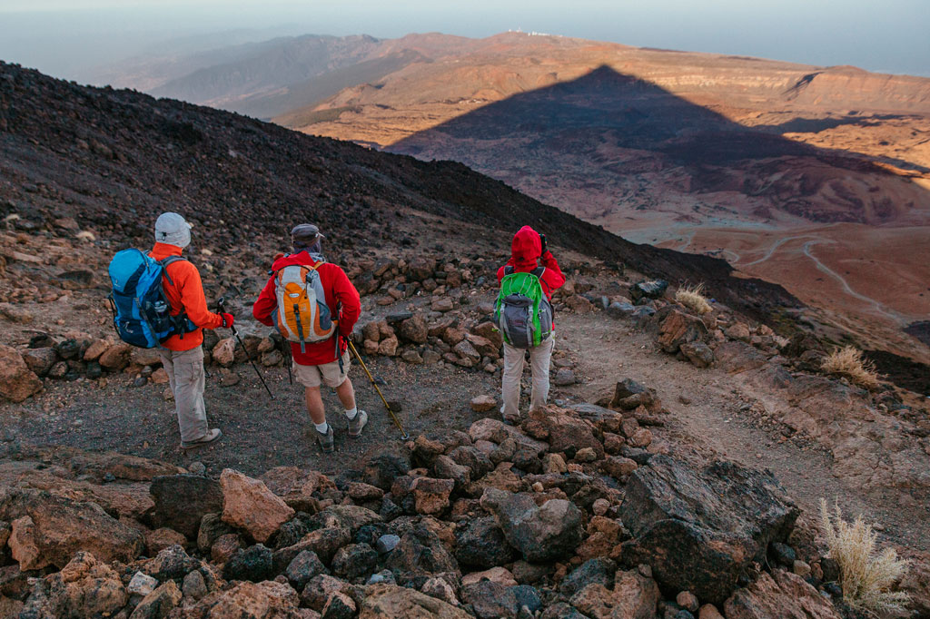 Drie wandelaars wandelen over rotsachtige paden in Nationaal Park Teide, Tenerife.