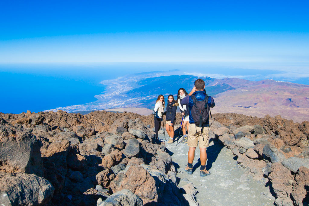 Groep mensen op een rotsachtig pad met zeezicht en landschappen van Tenerife.