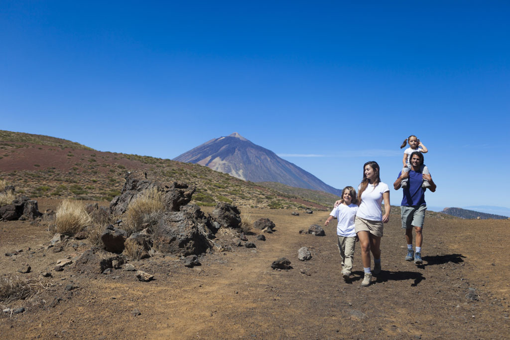 Familie wandelt bij de Teide-vulkaan op Tenerife onder een heldere lucht.