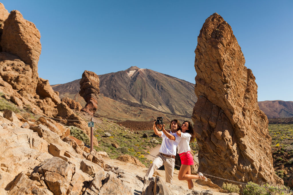 Mensen die selfies maken in het Nationaal Park Teide, Tenerife, met bergen op de achtergrond.