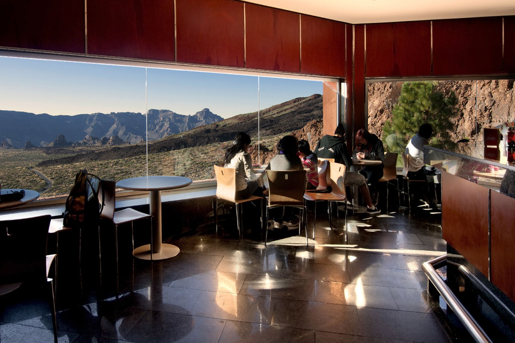 Uitzicht op de berg Teide vanuit een café op Tenerife met mensen die bij het raam zitten.