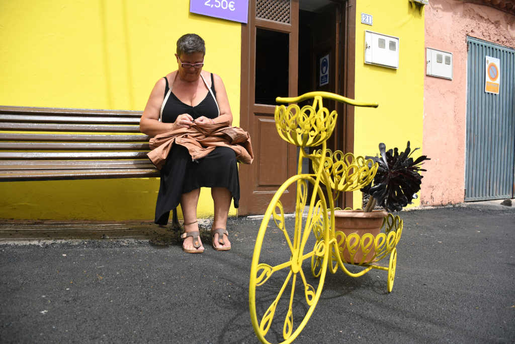 Vrouw die op een bankje naast een decoratieve fiets zit op Tenerife.