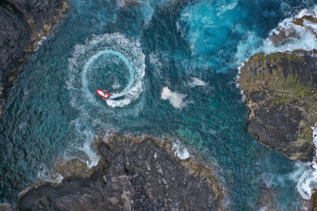 Rode boot die cirkels maakt in de kustwateren van Tenerife.