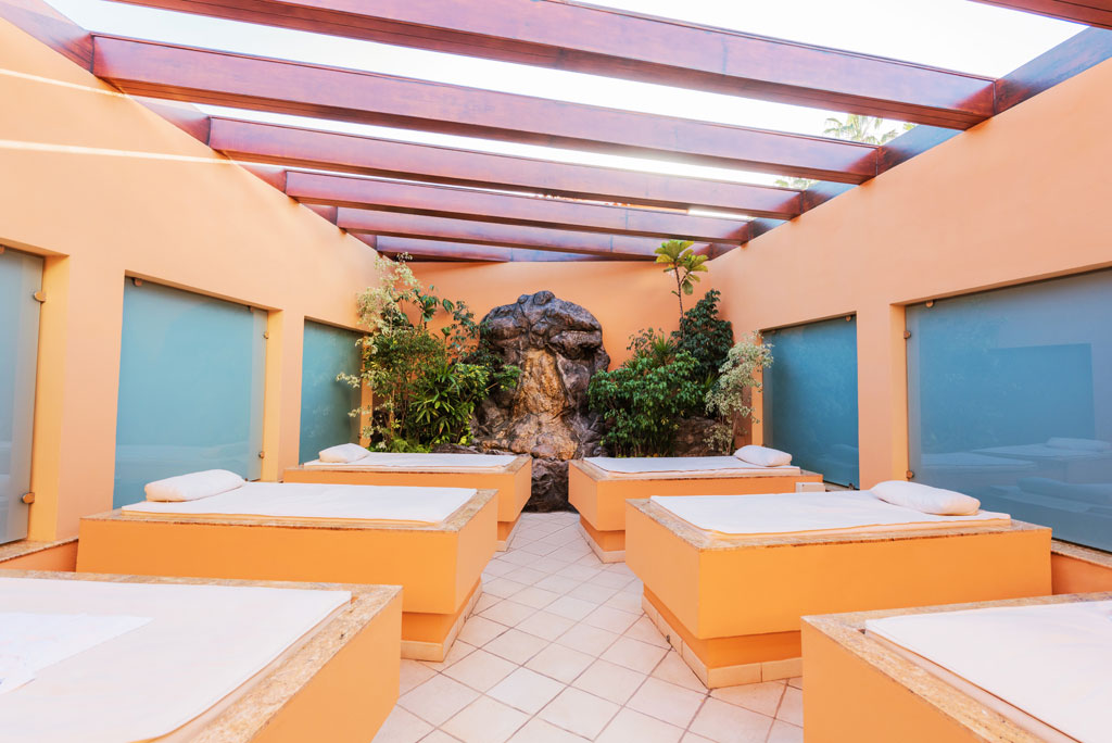 Spabedden in een binnenlounge op Tenerife, omringd door planten en natuurlijk licht.