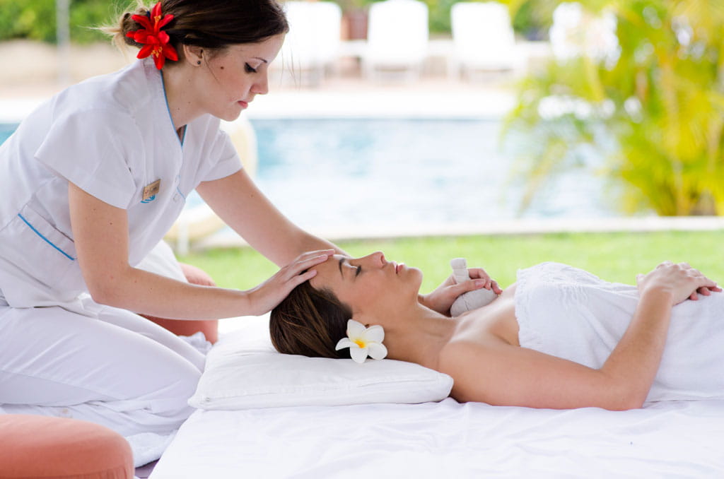 Therapeut geeft een massage aan een vrouw die bij het zwembad op Tenerife ligt.